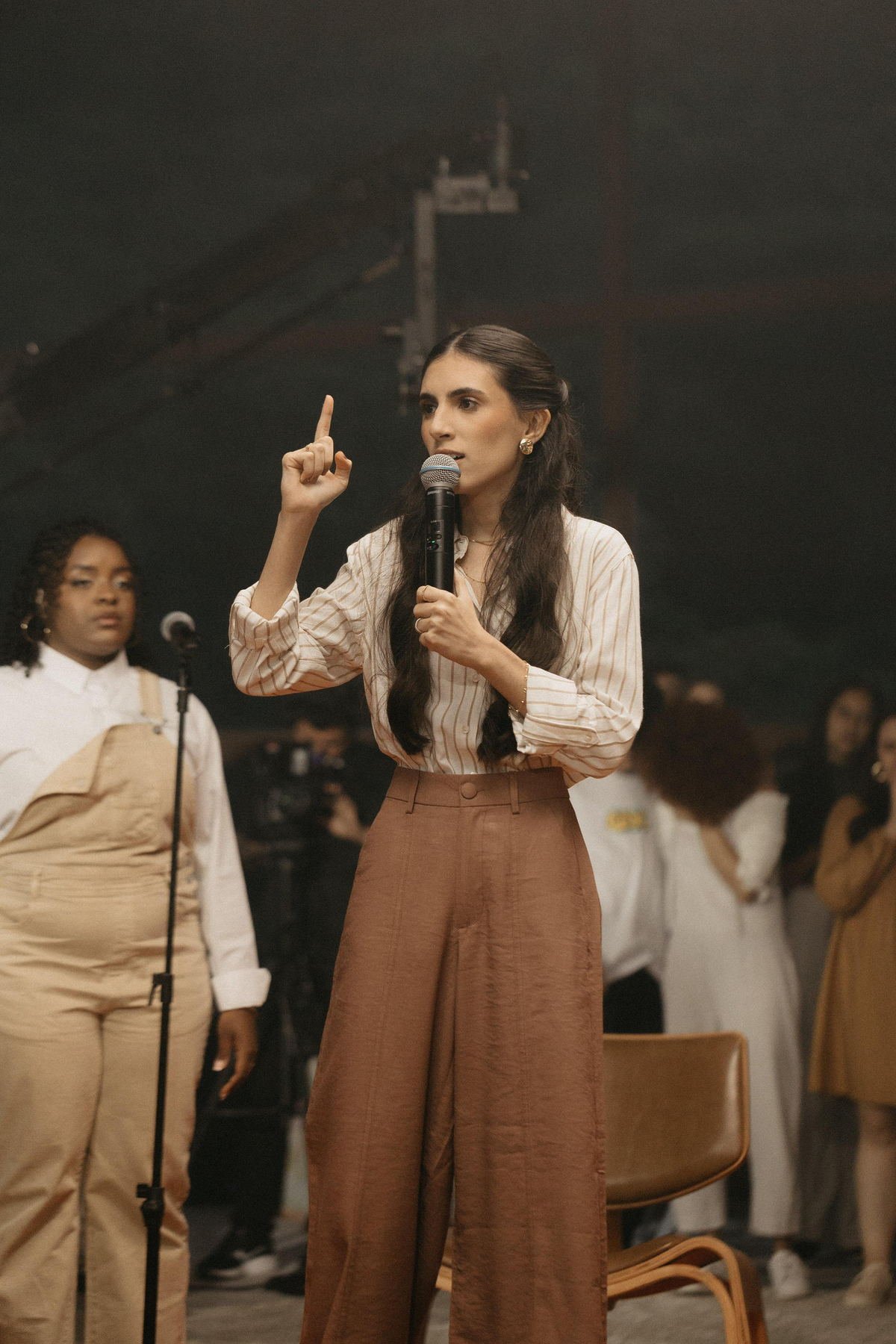 Thayna Azevedo pregando com microfone diante do público