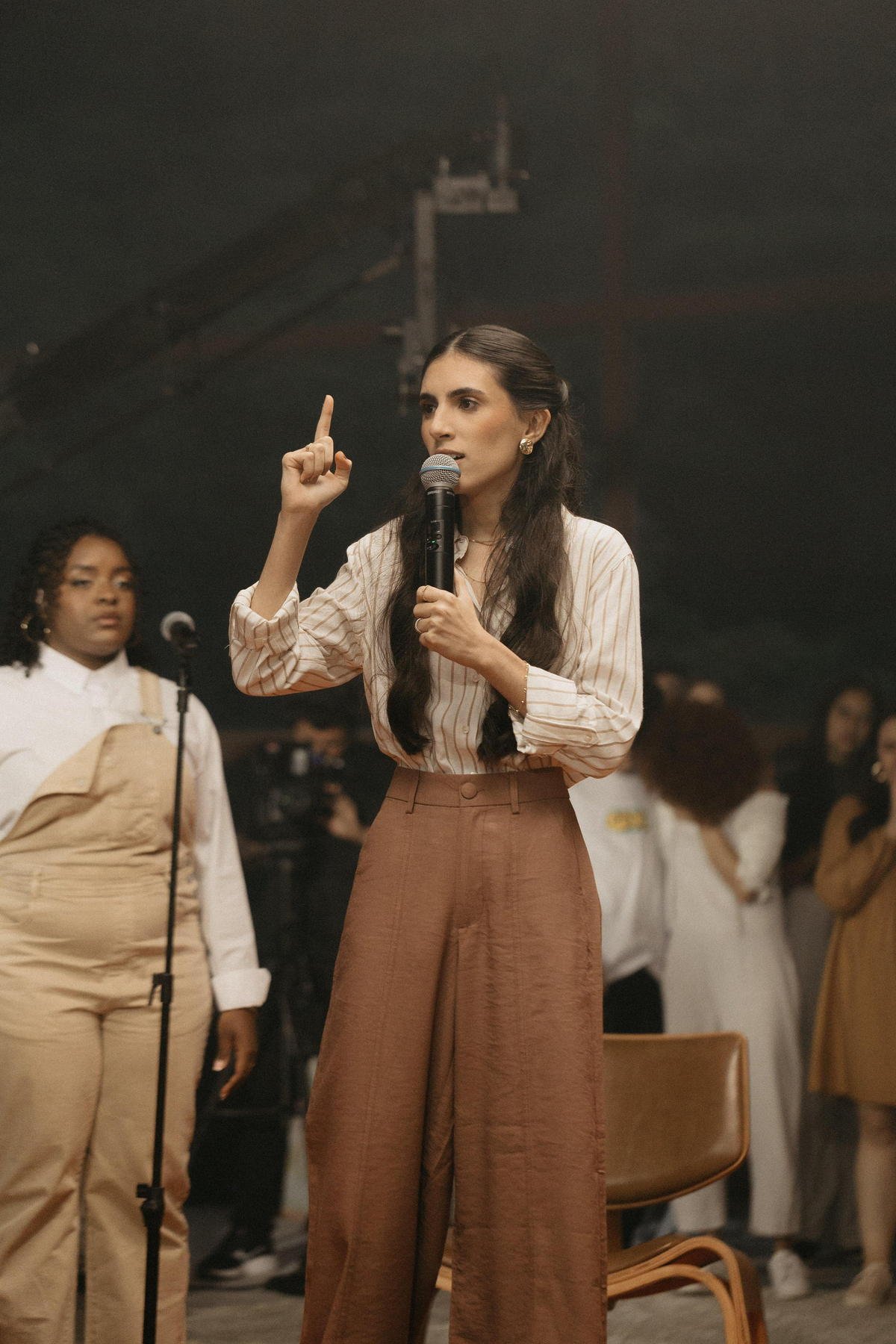 Thayna Azevedo pregando com microfone diante do público